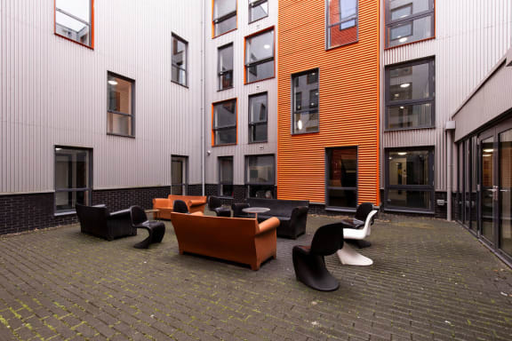 a courtyard with couches and chairs outside of a building