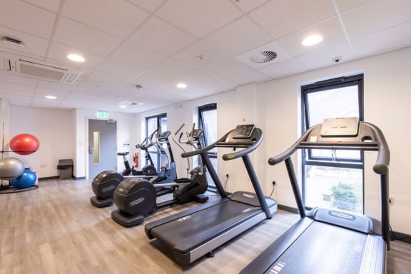 a gym with treadmills and other exercise equipment on a wooden floor