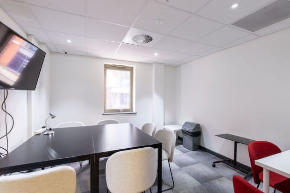 a conference room with a table and chairs and a television