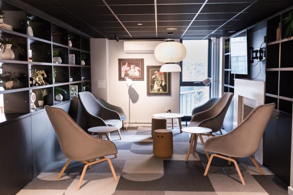 a lounge area with chairs and tables and a window