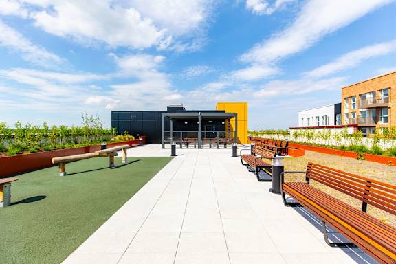 a roof terrace with benches and a building in the background