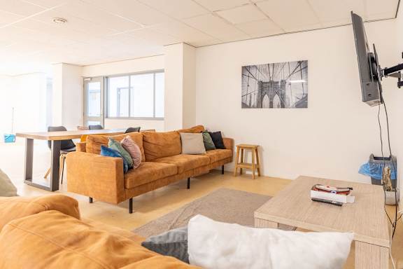 A living room with a yellow couch and a television.