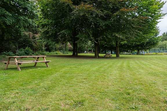 A picnic table sits in the middle of a grassy field.