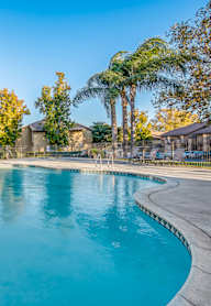 A swimming pool with a ladder in the foreground and a building in the background.