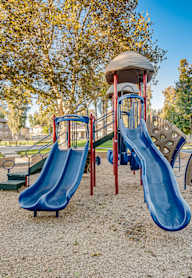 A playground with a blue slide and a red and grey slide.