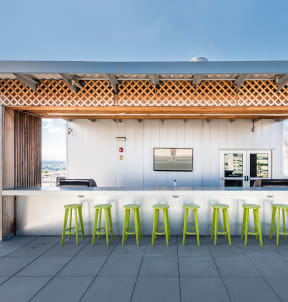 a rooftop bar with yellow stools and a white wall