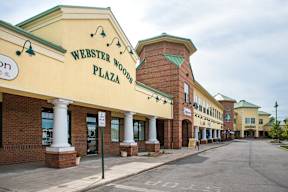 A street view of Webster Woods Plaza with a clear sky.