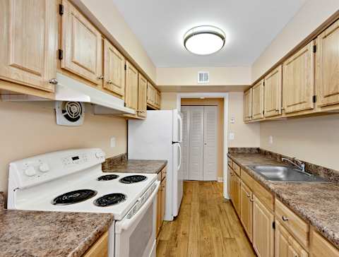 A kitchen with a white stove top oven and a white refrigerator.