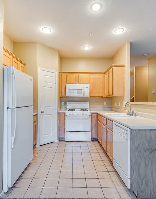 A kitchen with a white refrigerator, white sink, and white countertops.