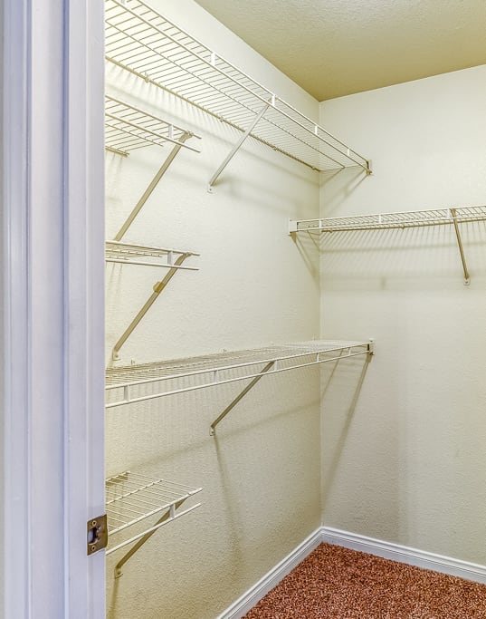 a walk in closet with white walls and shelves and a white door