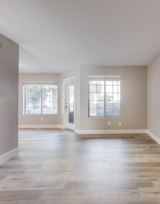 an empty living room with hardwood flooring and a window