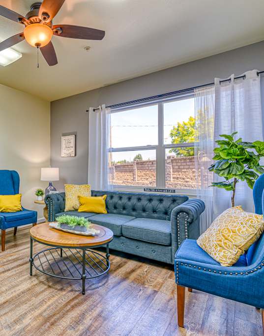 A living room with a blue chair and a green couch.