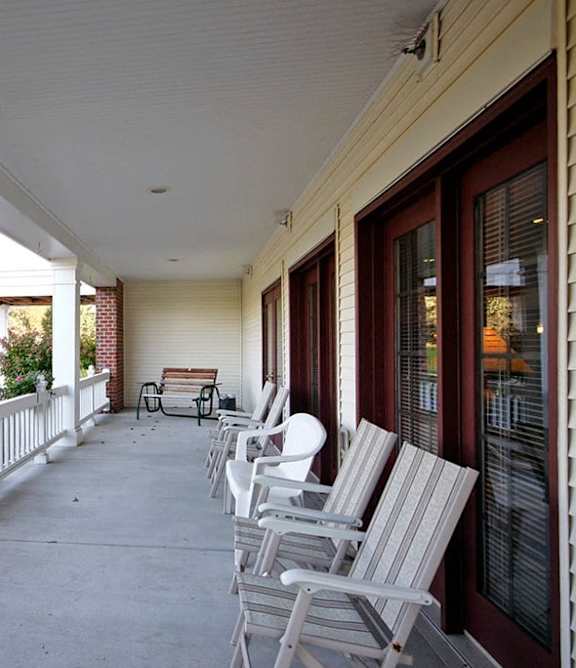 A porch with white railings and chairs.