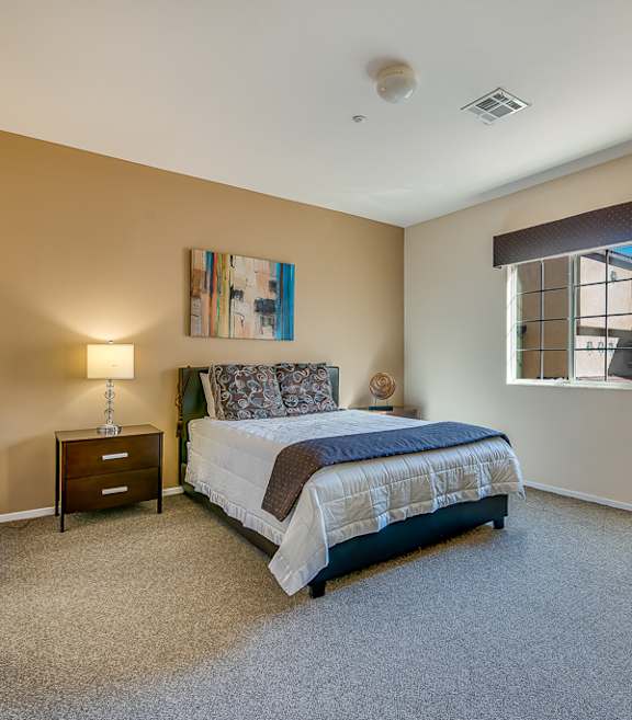 A bedroom with a bed, nightstand, and lamp.