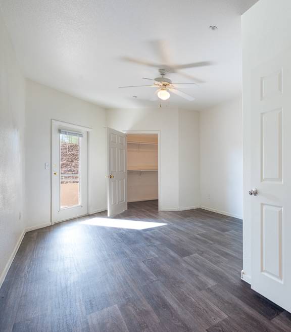 A room with a ceiling fan and a door.
