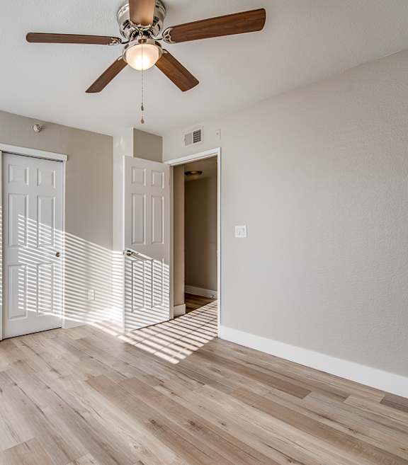 an empty living room with a ceiling fan and a staircase