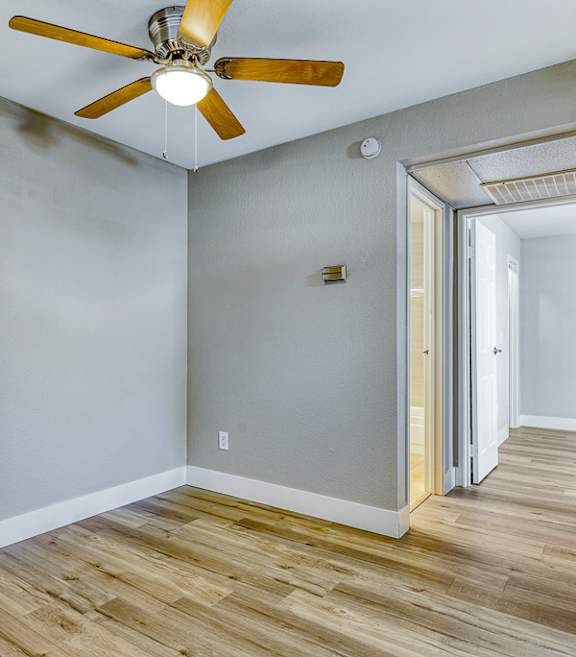 A room with a ceiling fan and wooden flooring.