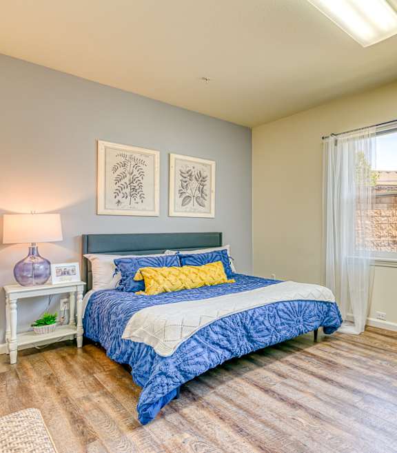 A bedroom with a bed, chair, and window.