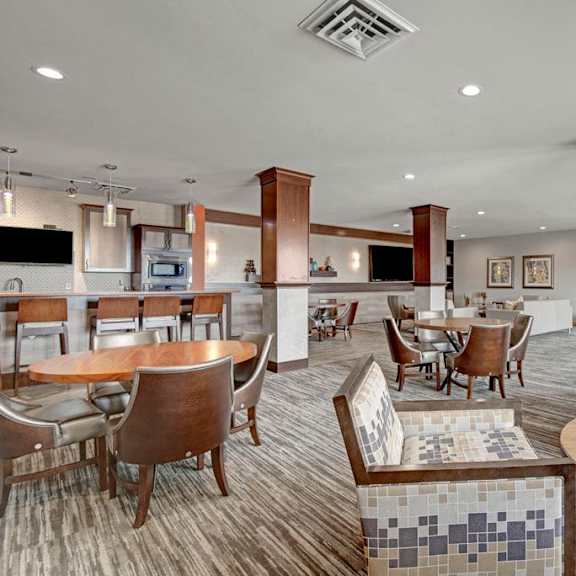 A gray and brown clubhouse with tables and chairs and a kitchen at Vue at Pinnacle Park.