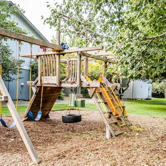 A wooden swing set with a slide and a tire swing.