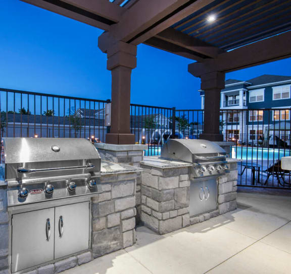two stainless steel barbecue grills on a patio with umbrellas