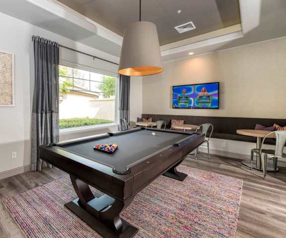 Game room with a pool table and smaller tables and chairs behind it at Artisan 8282. 