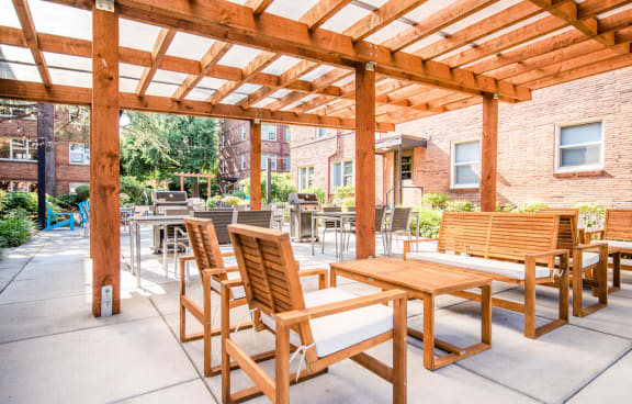 a patio with wooden tables and chairs and a pergola at Cadence, Seattle, WA, 98107