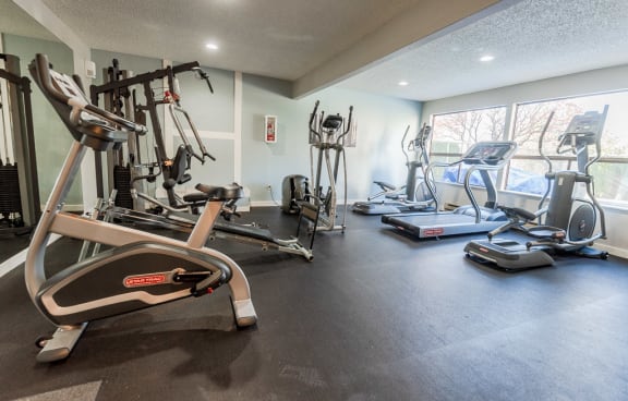 A gym with a variety of exercise equipment including treadmills, elliptical machines, and a stationary bike. at The Verandas, Tacoma, WA, 98466