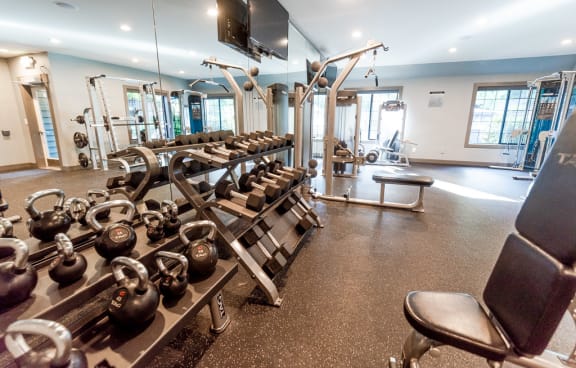 a fitness center with weights and cardio equipment and a television