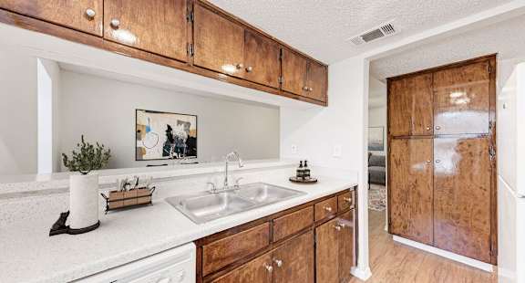 A kitchen with wooden cabinets and a white counter top.