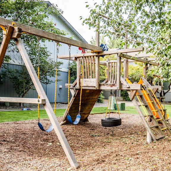 A wooden swing set with a slide and a tire swing.