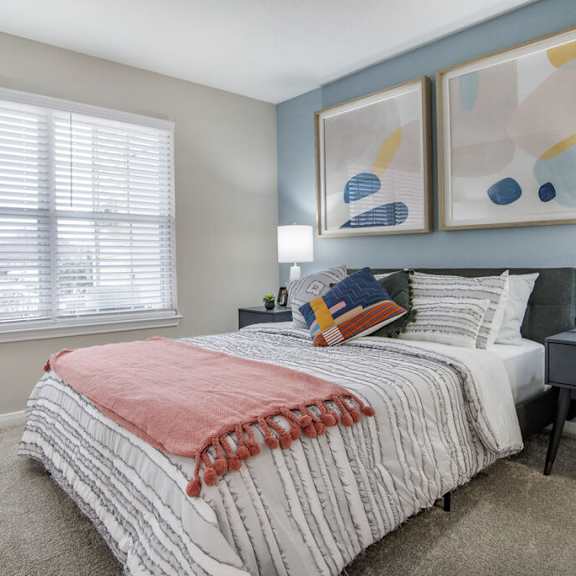 A bedroom with a large bed and two lamps.