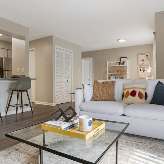 A modern living room with a white couch and a glass coffee table.