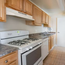 a kitchen with wooden cabinets and a white stove top oven at The Glendale Residence Apartments, Lanham, 20706