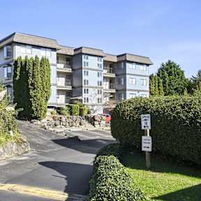 A row of townhouses with a car parked in front of the first one.