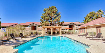 A swimming pool in a residential area with houses and trees in the background.