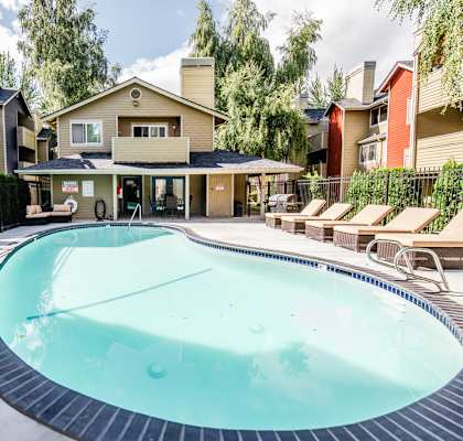 a resort style pool with lounge chairs and a building in the background at Cambridge on Seventh, Puyallup, WA, 98372