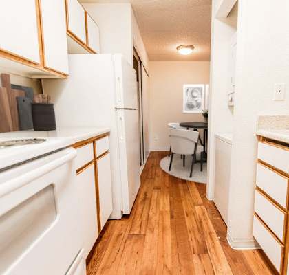 A kitchen with white appliances and wooden cabinets.