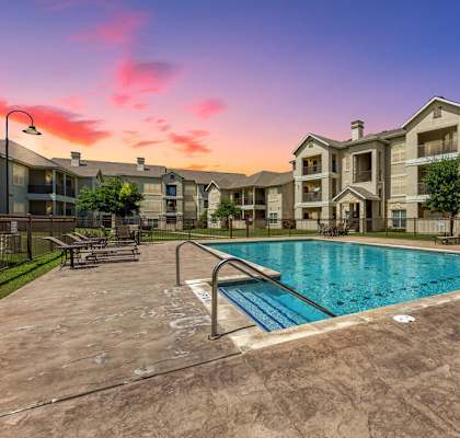 A large swimming pool in front of apartment buildings.
