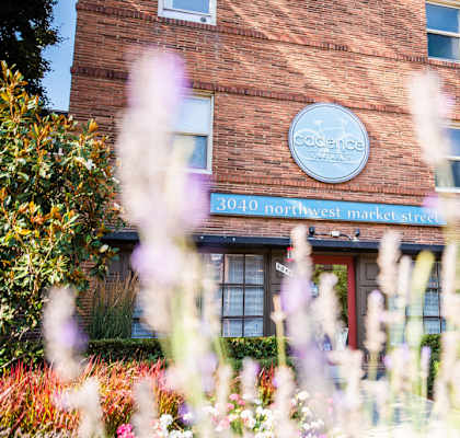 a brick building with a sign on it and flowers in front at Cadence, Seattle, WA, 98107