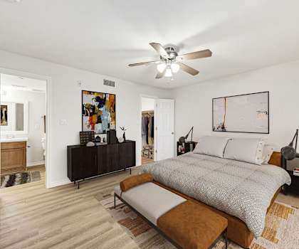 A bedroom with a bed, a bench, and a ceiling fan.