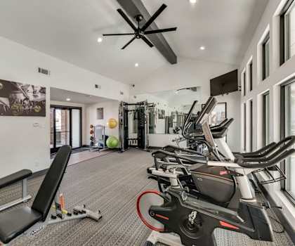 A gym with a variety of equipment including treadmills, weights, and exercise machines.