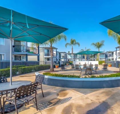 a courtyard with tables and chairs and umbrellas at the preserve at great pond apartments in