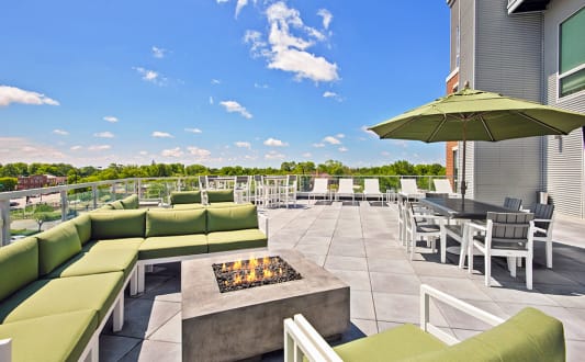 a patio with green couches and chairs and a fire pit