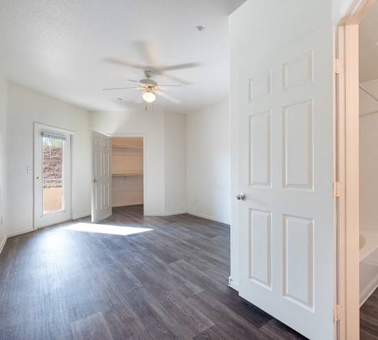 A room with a ceiling fan and a door.