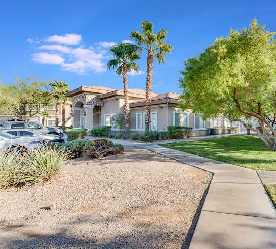 A residential area with a house, palm trees, and a clear sky.