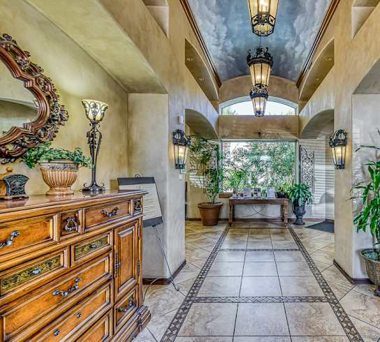 the entryway of a house with a tiled floor and a tree in the