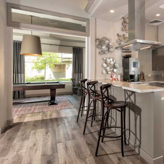 A kitchen with a large island with bar stools and stainless-steel appliances and a pool table in Artisan 8282.