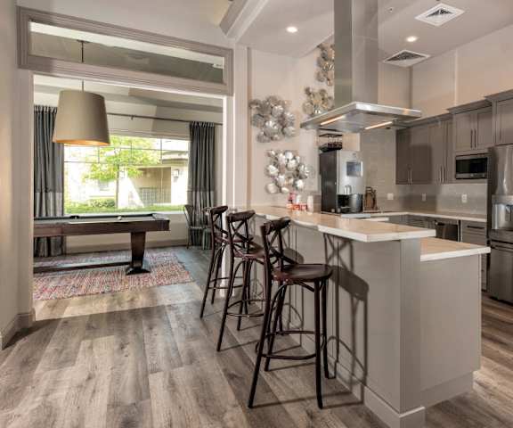 A kitchen with a large island with bar stools and stainless-steel appliances at Artisan 8282. 