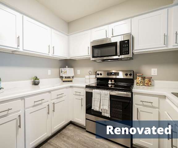 A large, modern kitchen with stainless steel appliances, white marble countertops with lots of room, and large, white wooden cabinets at Villas at Countryside Apartment Homes. 